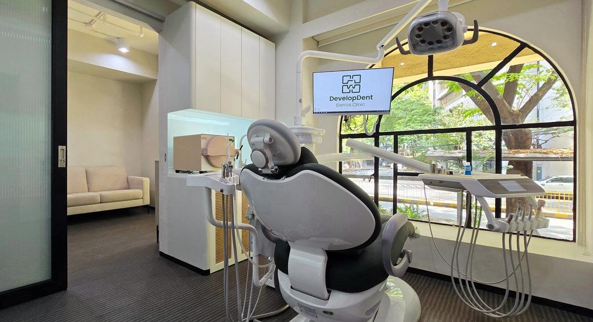Treatment room at DevelopDent Dental Clinic in Legazpi Village, Makati, with intraoral camera screen showing the DevelopDent logo and an arched window looking out on Paseo de Roxas